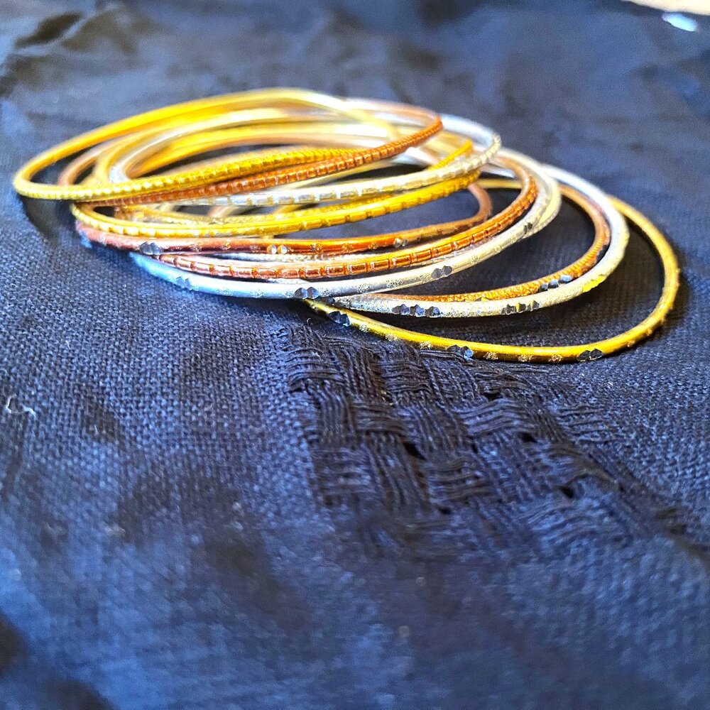 12 Gold, Silver, and Bronze Colored Bangles and a Single Gold-Colored Bangle